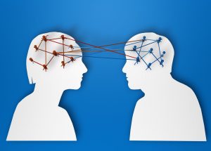 Cutouts of two human heads with pins and strings connecting them. Sharing thoughts.
